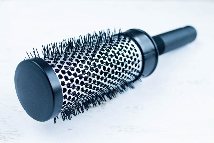 A black, rounded hair brush with synthetic bristles