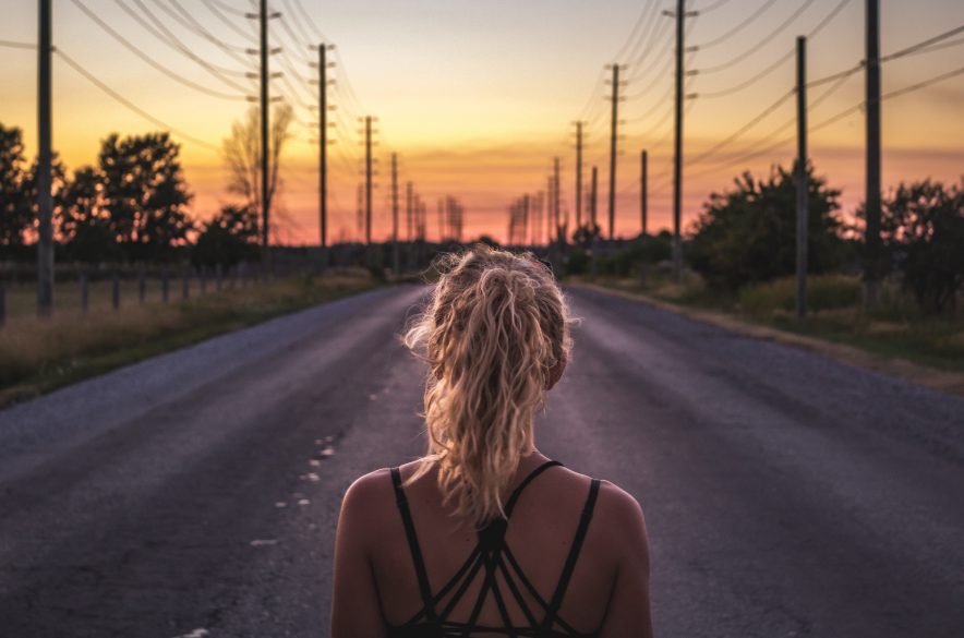 A girl standing on a road watching the sunset