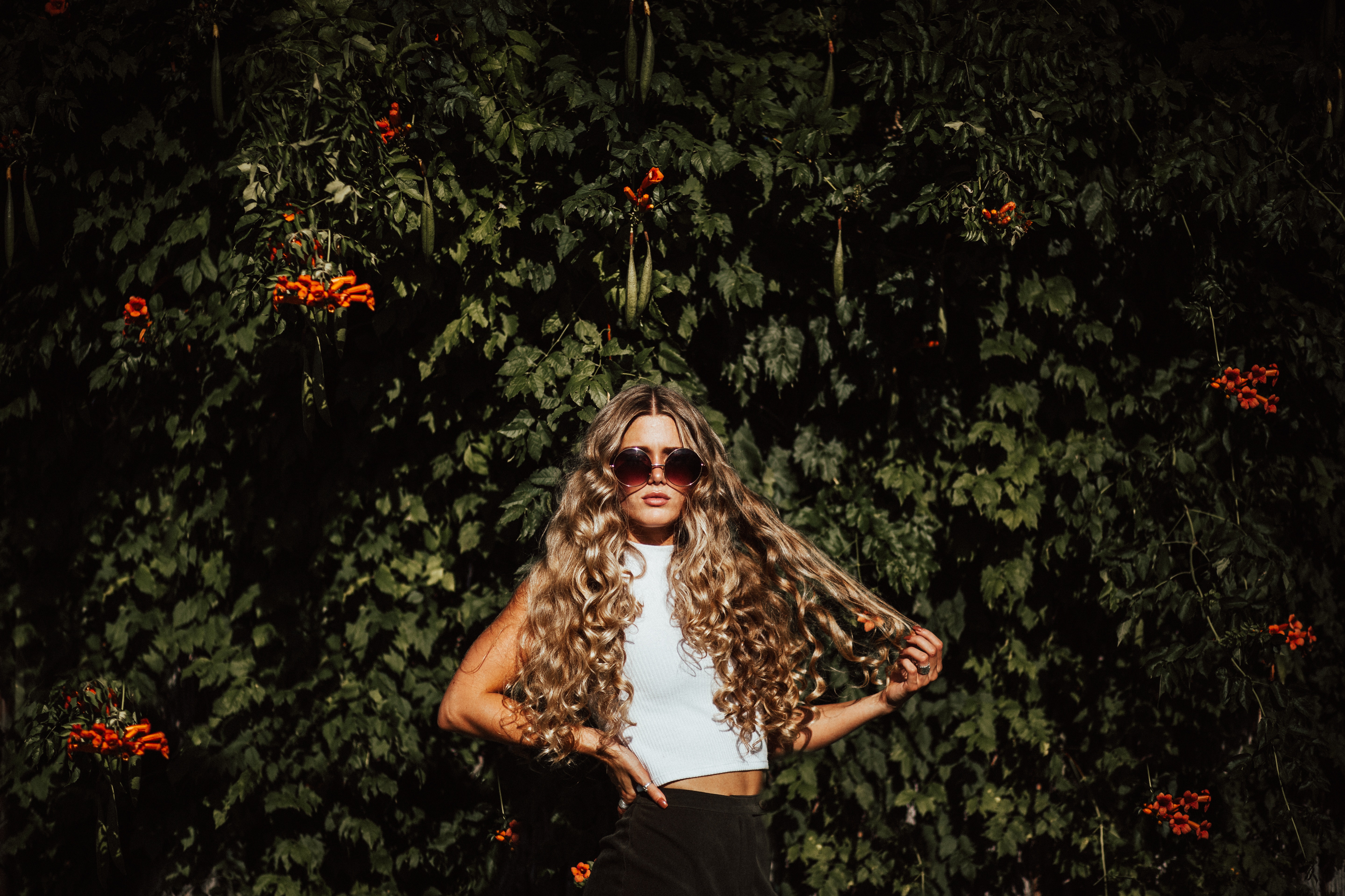 A girl outside against a flowering bush with long hair ready for the summer months